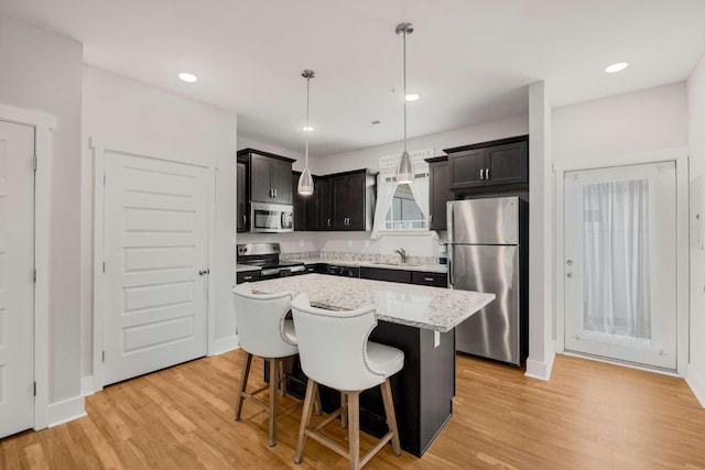 kitchen with a center island, a kitchen breakfast bar, sink, hanging light fixtures, and stainless steel appliances