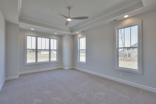 carpeted empty room with ceiling fan and a raised ceiling