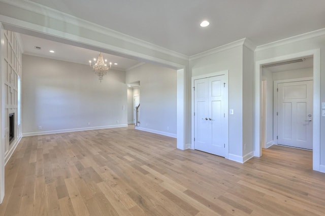 spare room featuring light hardwood / wood-style flooring, crown molding, and a notable chandelier