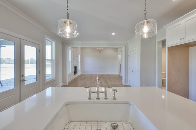 kitchen featuring white cabinetry, french doors, hanging light fixtures, and ornamental molding