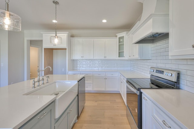 kitchen featuring white cabinets, hanging light fixtures, premium range hood, and appliances with stainless steel finishes