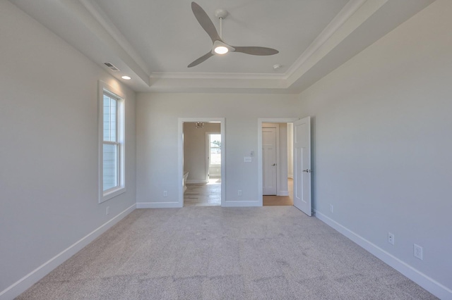 carpeted spare room with a tray ceiling, ceiling fan, and crown molding