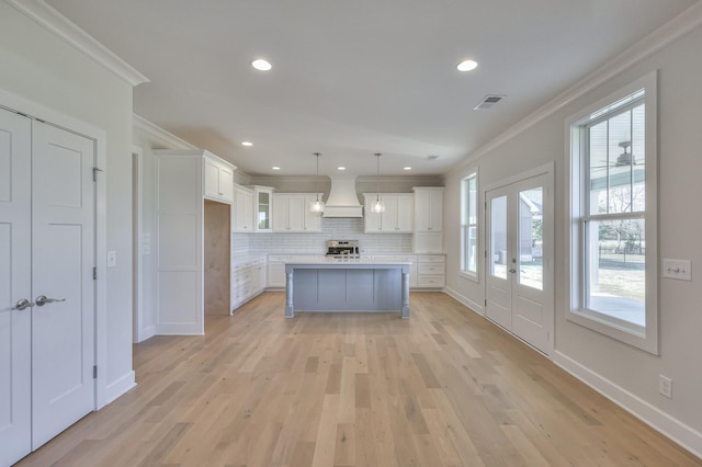 kitchen with pendant lighting, custom exhaust hood, backsplash, french doors, and white cabinetry