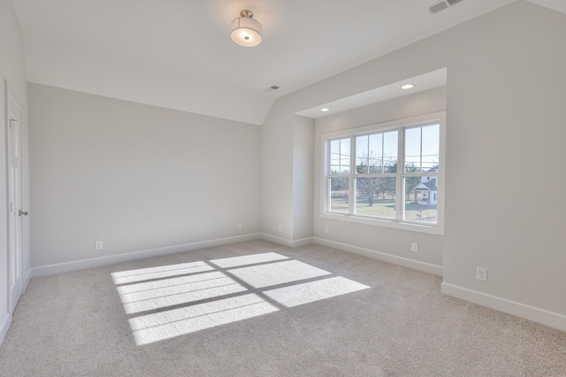 spare room featuring light carpet and vaulted ceiling