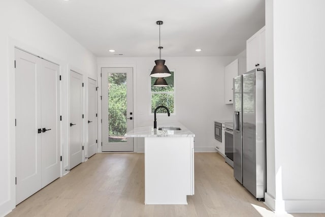 kitchen with white cabinetry, sink, light hardwood / wood-style flooring, stainless steel fridge, and pendant lighting