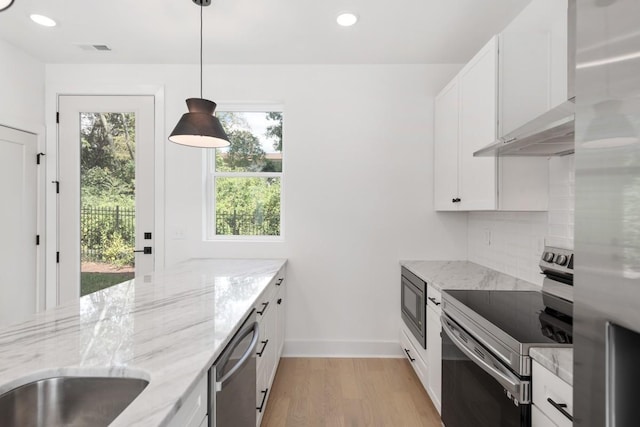 kitchen featuring pendant lighting, decorative backsplash, light stone counters, white cabinetry, and stainless steel appliances