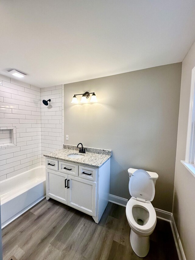 full bathroom featuring toilet, vanity, tiled shower / bath combo, and hardwood / wood-style flooring