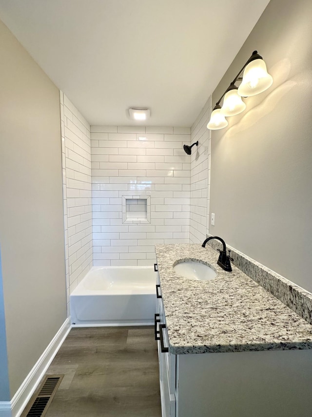 bathroom with tiled shower / bath, vanity, and hardwood / wood-style flooring