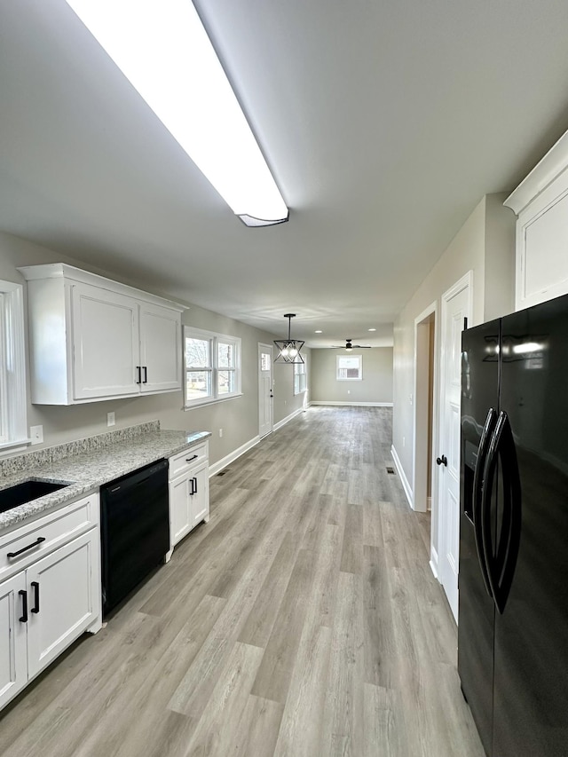 kitchen featuring black appliances, ceiling fan with notable chandelier, light stone counters, and white cabinetry