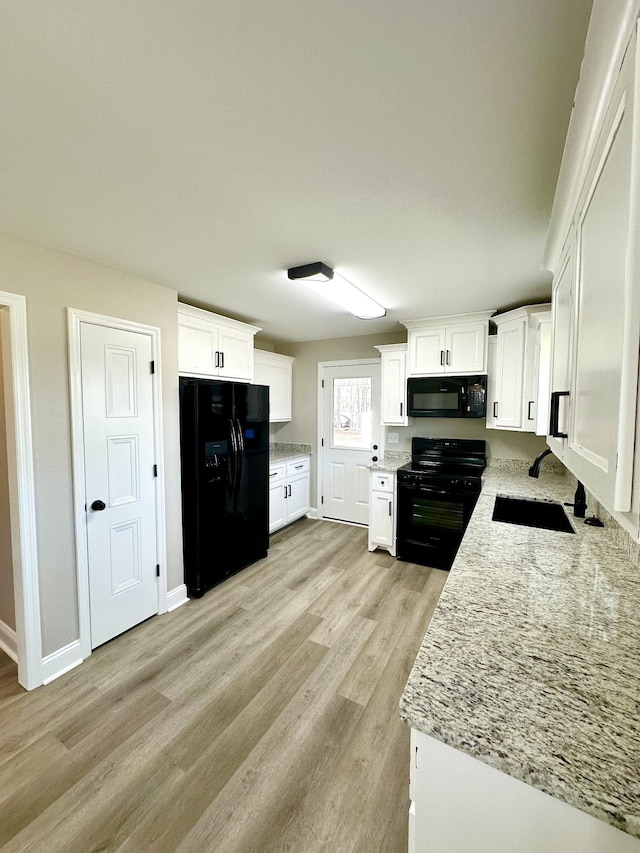 kitchen featuring black appliances, sink, light hardwood / wood-style flooring, light stone countertops, and white cabinetry