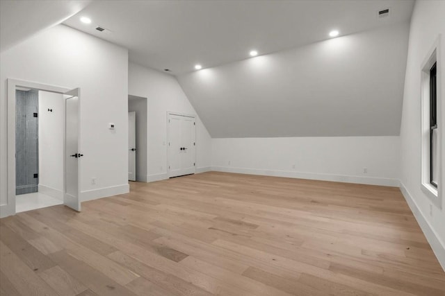 additional living space featuring vaulted ceiling and light hardwood / wood-style floors