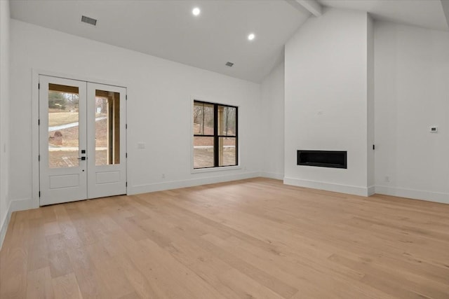 unfurnished living room with beamed ceiling, high vaulted ceiling, french doors, and light wood-type flooring