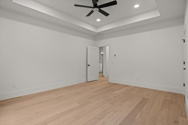 unfurnished room featuring ceiling fan, a tray ceiling, and light hardwood / wood-style floors