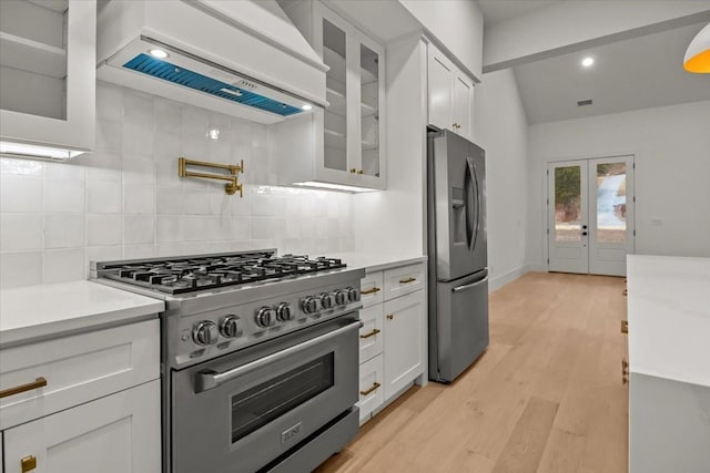 kitchen featuring stainless steel appliances, custom exhaust hood, white cabinetry, and decorative backsplash