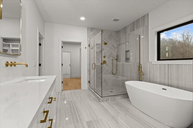 bathroom with vanity, shower with separate bathtub, and tile walls