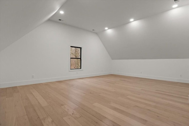 additional living space with vaulted ceiling and light hardwood / wood-style flooring