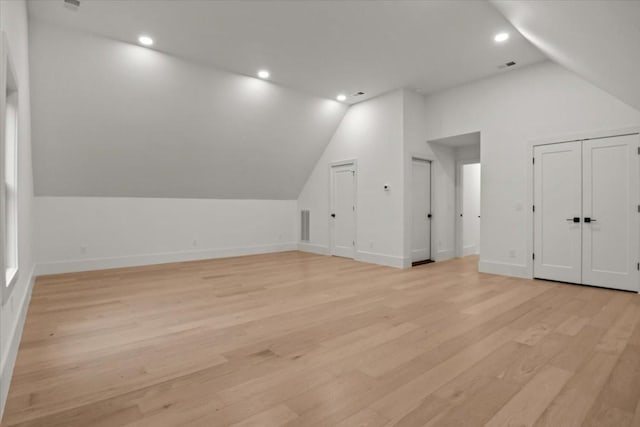 additional living space with light hardwood / wood-style flooring and vaulted ceiling