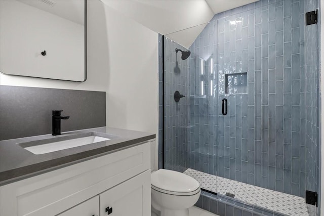 bathroom featuring vanity, toilet, a shower with shower door, and vaulted ceiling