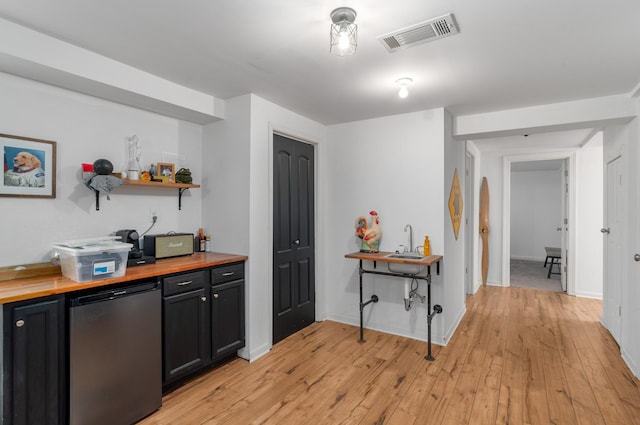 bar featuring light wood-type flooring, refrigerator, butcher block counters, and sink