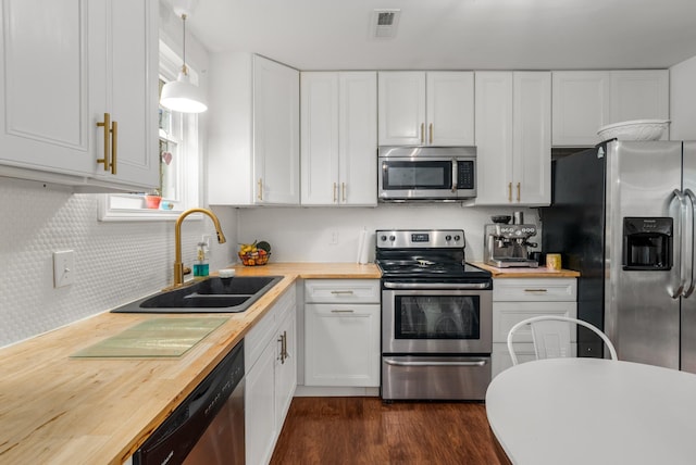 kitchen with butcher block counters, white cabinetry, sink, pendant lighting, and appliances with stainless steel finishes