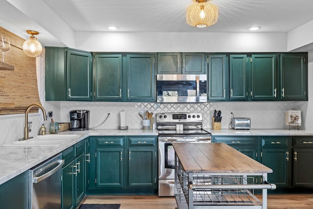 kitchen with tasteful backsplash, green cabinets, sink, and stainless steel appliances