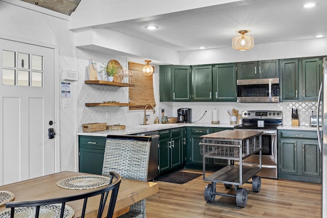 kitchen featuring appliances with stainless steel finishes, light hardwood / wood-style flooring, green cabinets, and sink