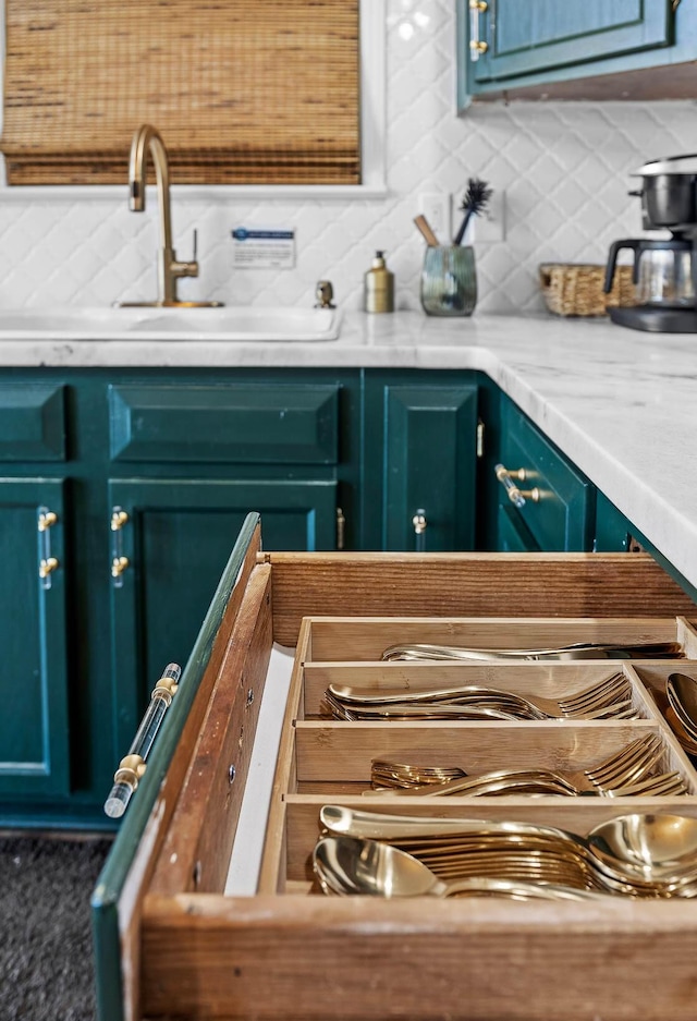 interior details featuring backsplash, blue cabinetry, and sink