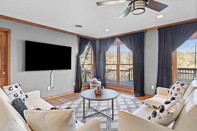 living room with ceiling fan, ornamental molding, and light wood-type flooring