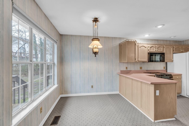 kitchen with kitchen peninsula, pendant lighting, light brown cabinetry, and black appliances