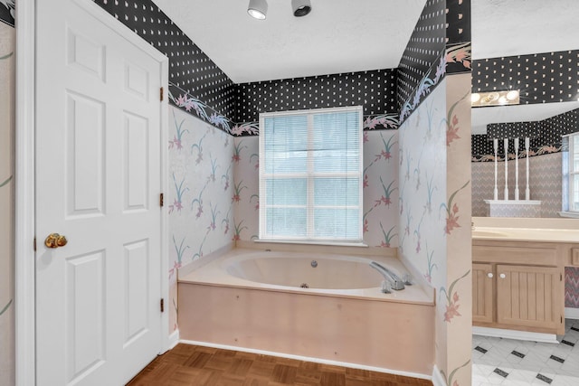 bathroom with a washtub, a textured ceiling, and vanity