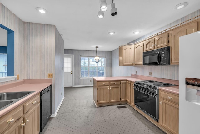 kitchen featuring kitchen peninsula, light brown cabinetry, decorative light fixtures, and black appliances