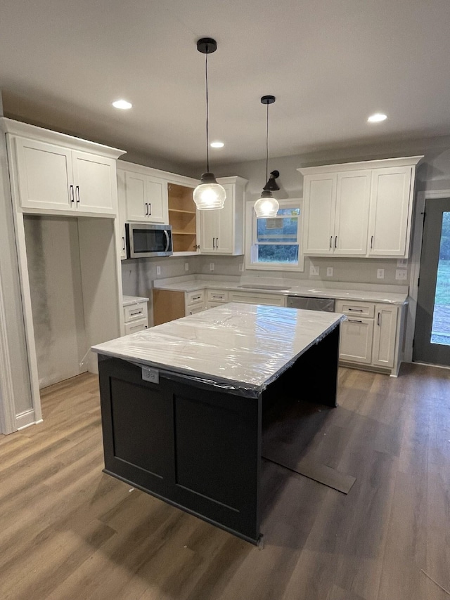 kitchen with pendant lighting, a center island, light stone countertops, appliances with stainless steel finishes, and white cabinetry