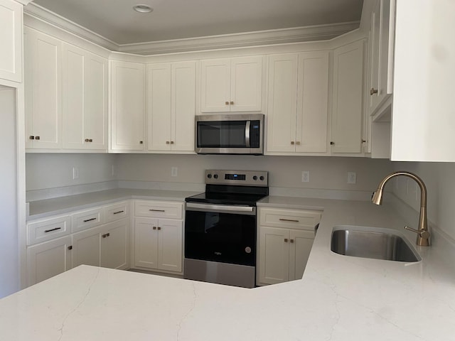 kitchen featuring white cabinets, appliances with stainless steel finishes, light stone counters, and sink