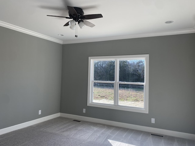 carpeted spare room featuring ceiling fan, crown molding, and plenty of natural light