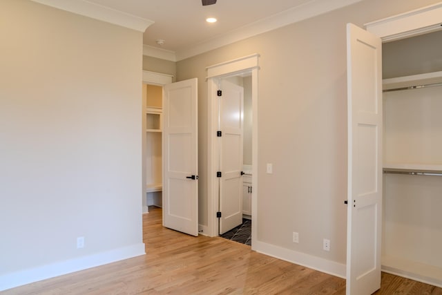 unfurnished bedroom with light wood-type flooring, crown molding, and a closet