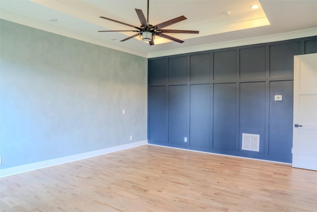 unfurnished bedroom featuring light wood-type flooring, a raised ceiling, and ceiling fan