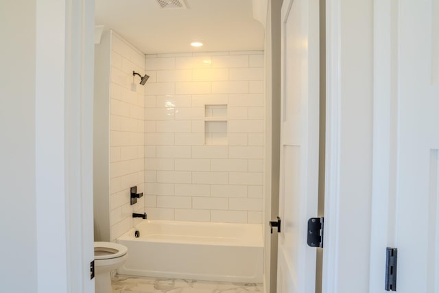 bathroom with tiled shower / bath combo and toilet