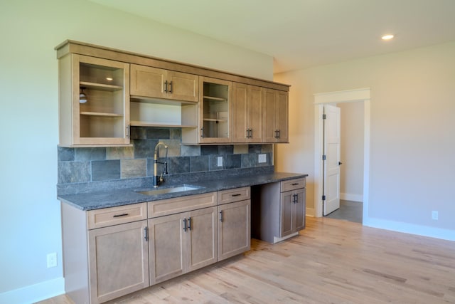 kitchen with light hardwood / wood-style flooring, sink, dark stone counters, and tasteful backsplash