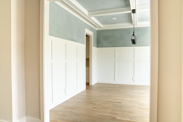 hallway with beam ceiling, light wood-type flooring, ornamental molding, and coffered ceiling