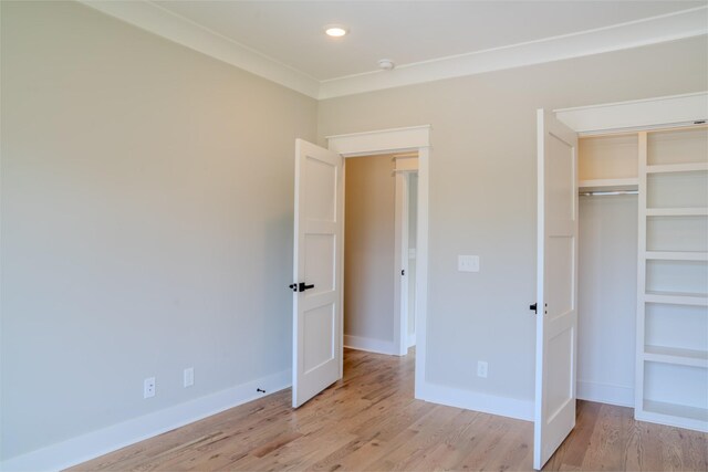 unfurnished bedroom featuring light hardwood / wood-style floors, a closet, and crown molding