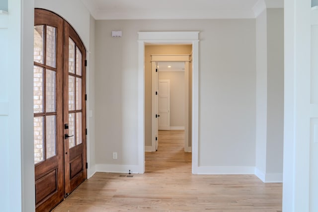 entrance foyer with ornamental molding, light hardwood / wood-style flooring, and french doors