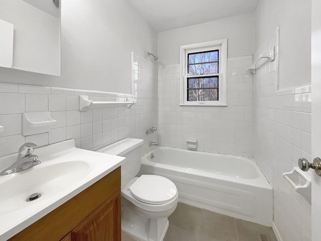 full bathroom with vanity, tile patterned floors, tiled shower / bath, toilet, and tile walls