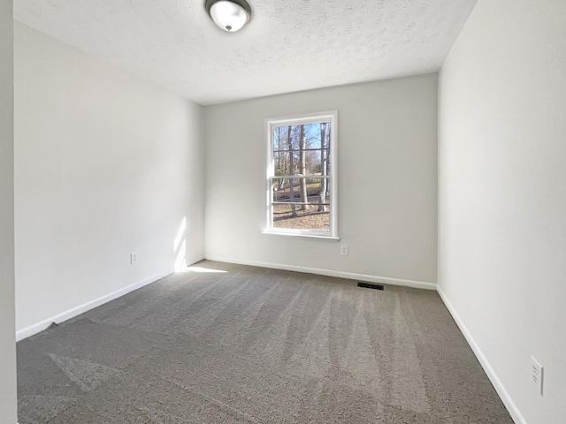 empty room with dark colored carpet and a textured ceiling