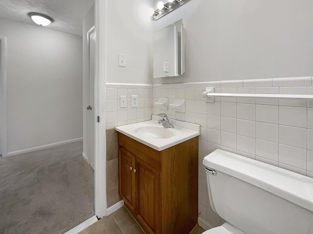 bathroom featuring tile patterned flooring, vanity, toilet, and tile walls