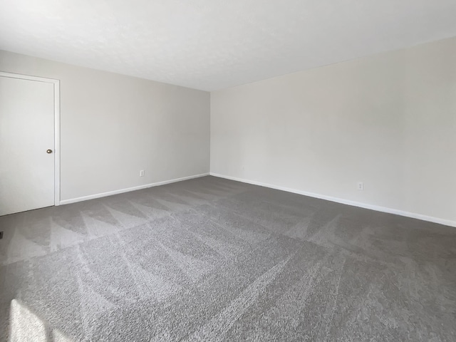 unfurnished room with dark carpet