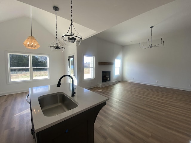 kitchen featuring dark wood-type flooring, sink, pendant lighting, a center island with sink, and high vaulted ceiling