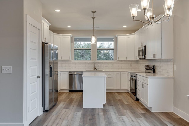 kitchen featuring pendant lighting, a center island, white cabinets, and appliances with stainless steel finishes