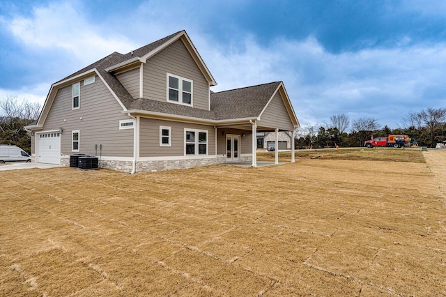 rear view of property featuring central AC unit and a garage