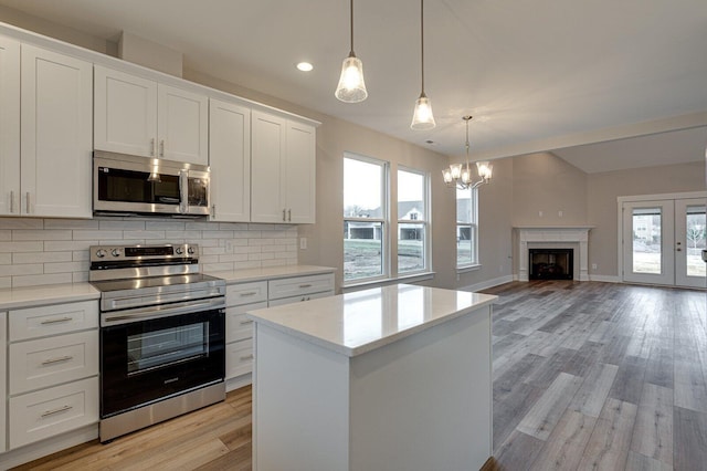 kitchen with white cabinetry, a center island, hanging light fixtures, stainless steel appliances, and backsplash