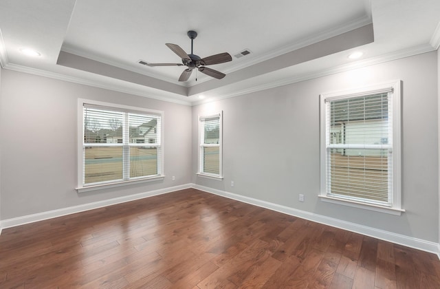 empty room featuring a tray ceiling, ornamental molding, dark hardwood / wood-style floors, and ceiling fan